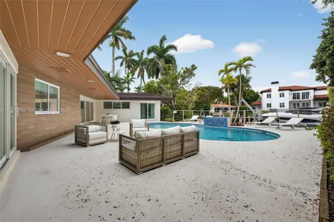 a view of a swimming pool with couches potted plants and palm tree