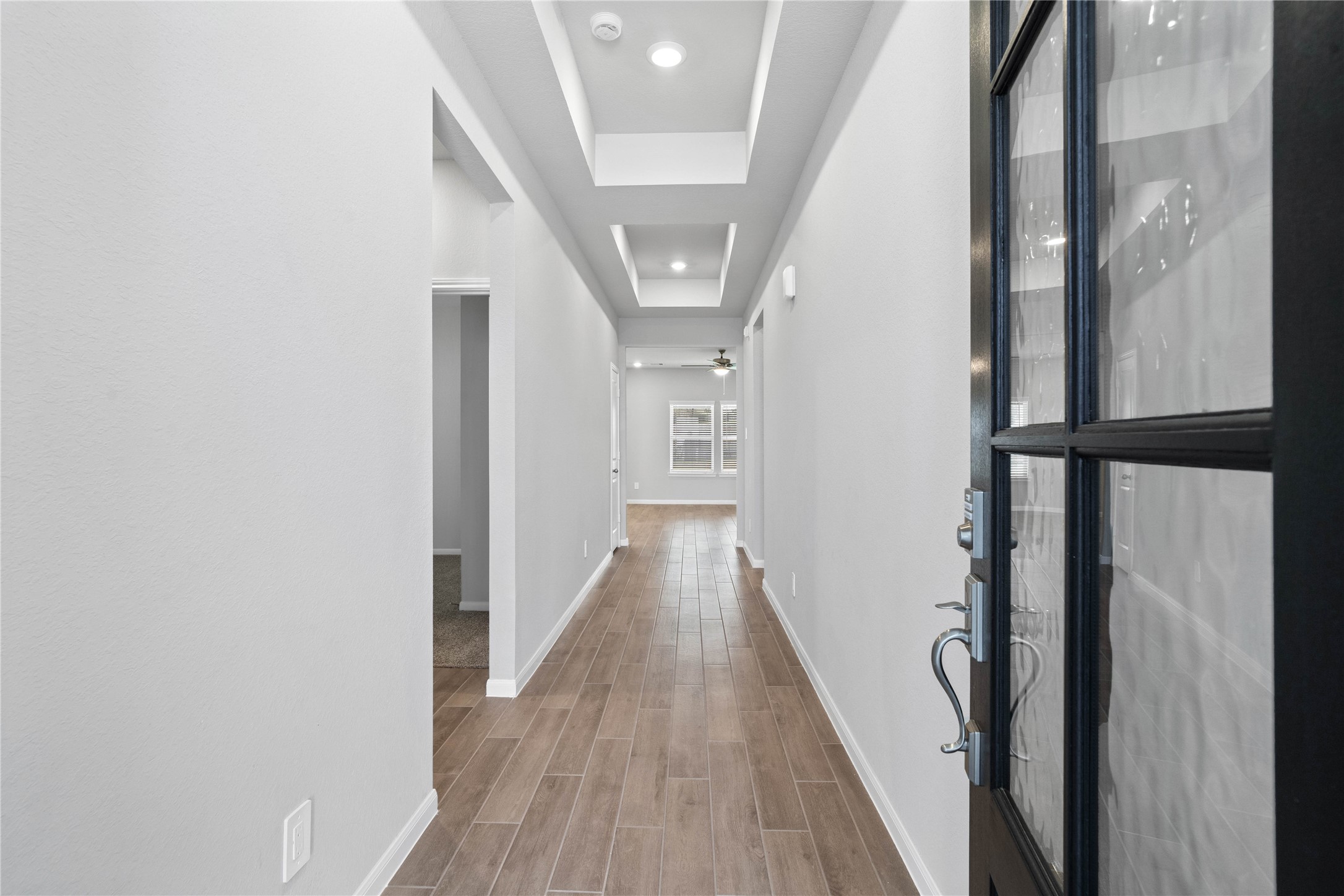 19645 Montgomery Rdg Way Montgomery, TX 77316 - Photo 6 of 41 This entryway features a modern, open-concept design. The long, bright corridor utilizes a neutral color palette, recessed lighting, and luxury vinyl flooring to lead the eye toward the home's main living area.