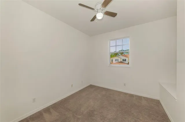 an empty room with a window and a fan