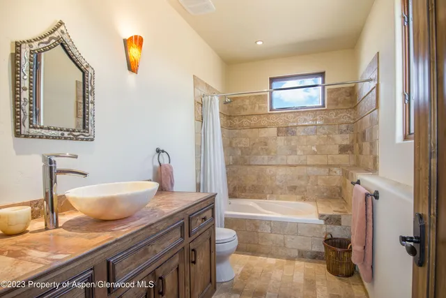 a bathroom with a granite countertop sink a toilet and shower