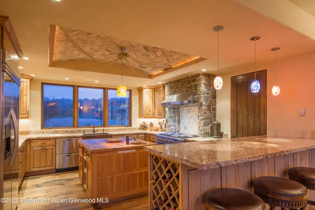 a kitchen with stainless steel appliances granite countertop a sink a stove and a wooden floors