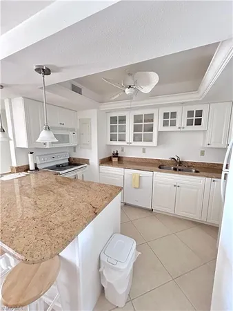 a large white kitchen with a stove a sink a microwave and dining table