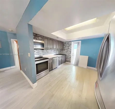 a large kitchen with stainless steel appliances granite countertop a stove a sink dishwasher and a refrigerator