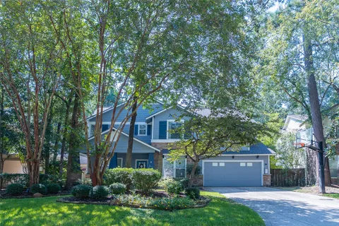 a front view of a house with a garden and trees