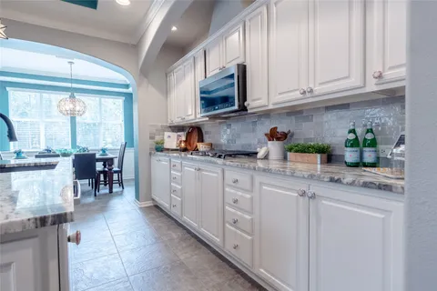 a kitchen with stainless steel appliances granite countertop a sink a stove a refrigerator cabinets and chairs