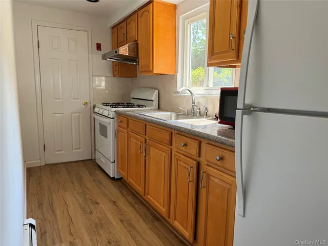 a kitchen with stainless steel appliances granite countertop a refrigerator a sink dishwasher and wooden cabinets with wooden floor