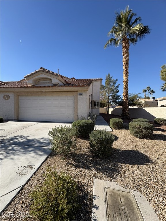 Mediterranean / spanish-style house featuring driveway, a tiled roof, an attached garage, and stucco siding