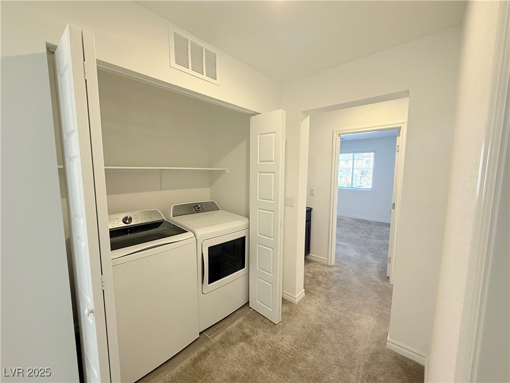 10772 Astell Isle Court Las Vegas, NV 89166 - Photo 11 of 32 Laundry room featuring light carpet and washing machine and clothes dryer