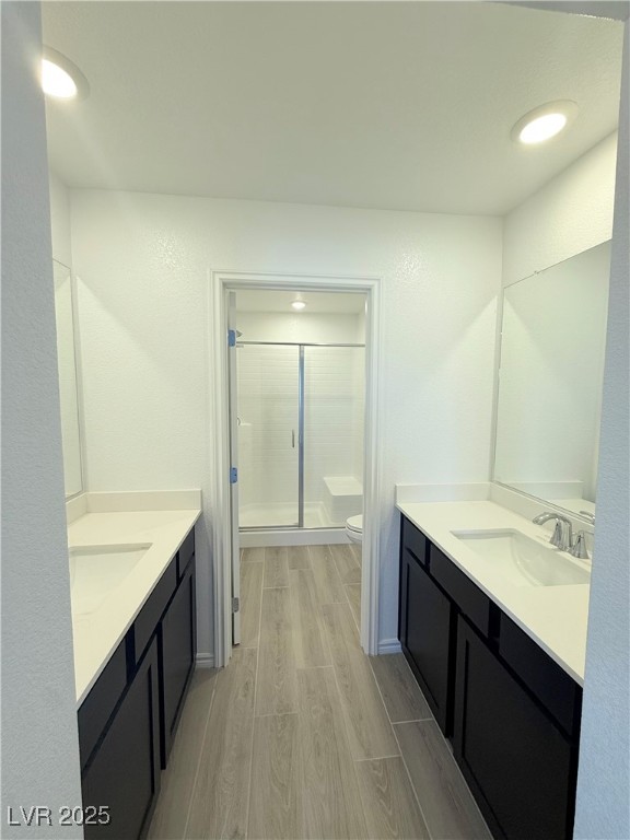 10772 Astell Isle Court Las Vegas, NV 89166 - Photo 26 of 32 Primary bathroom with wood tiled floors, a stall shower, two vanities, and recessed lighting