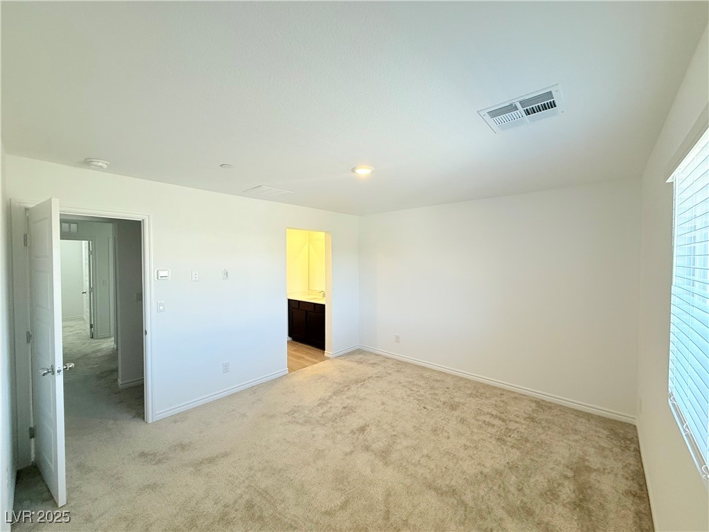 10772 Astell Isle Court Las Vegas, NV 89166 - Photo 27 of 32 Primary Bedroom with light colored carpet, ensuite bath, and recessed lighting