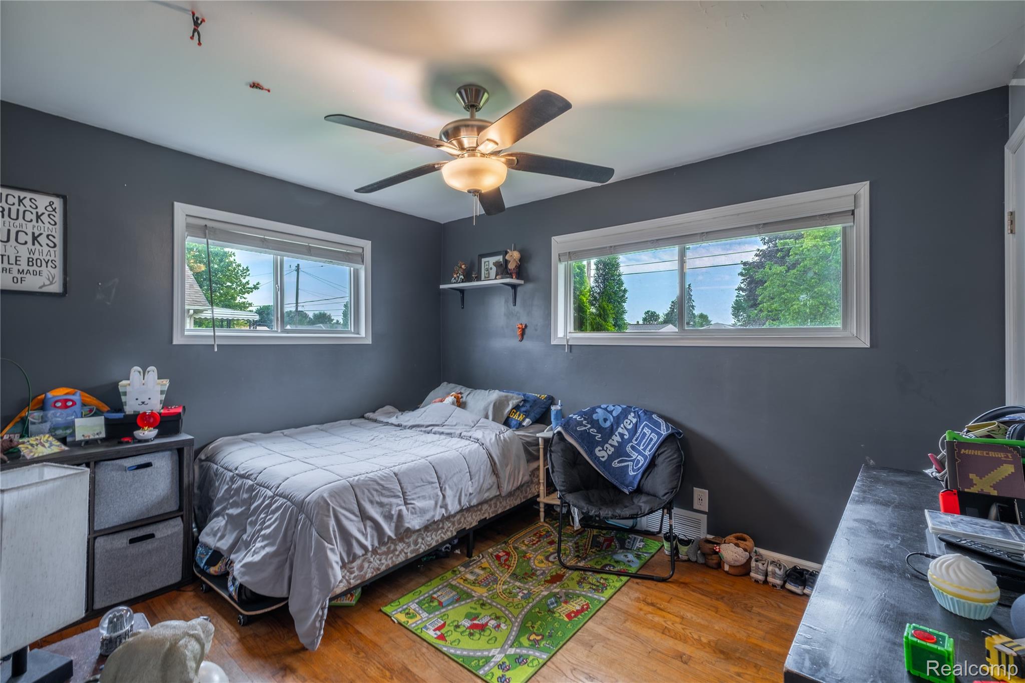 7800 Maple Street Birch Run, MI 48415 - Photo 12 of 29 Bedroom featuring wood-finish flooring, two large windows, a ceiling fan with integrated lighting, and dark gray painted walls