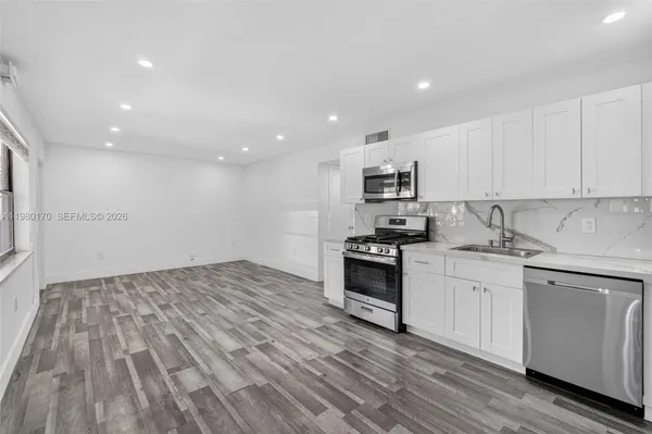 a kitchen with granite countertop a refrigerator stove top oven and sink