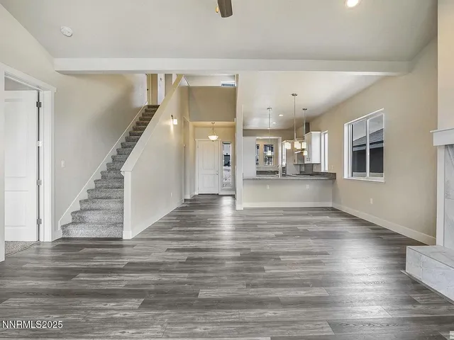 a view of a living room with wooden floor and kitchen view