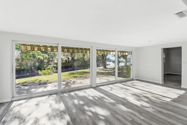 a view of an empty room with wooden floor and a floor to ceiling window
