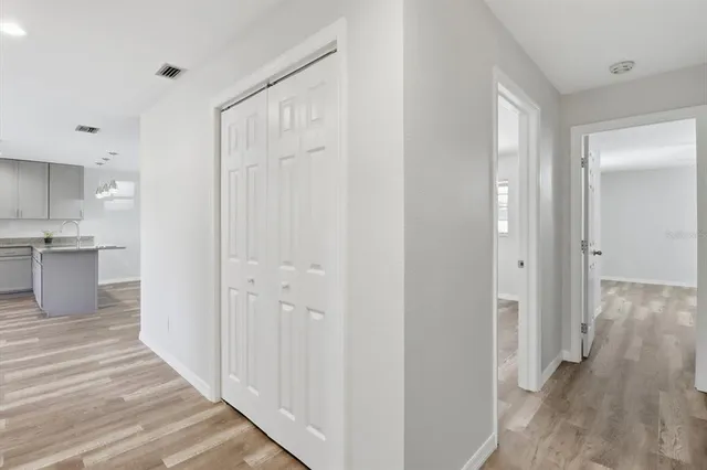 a view of a hallway with wooden floor and a kitchen