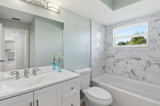 a bathroom with a granite countertop sink a toilet and bathtub