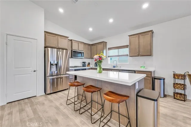 a kitchen with stainless steel appliances granite countertop a dining table chairs refrigerator and microwave