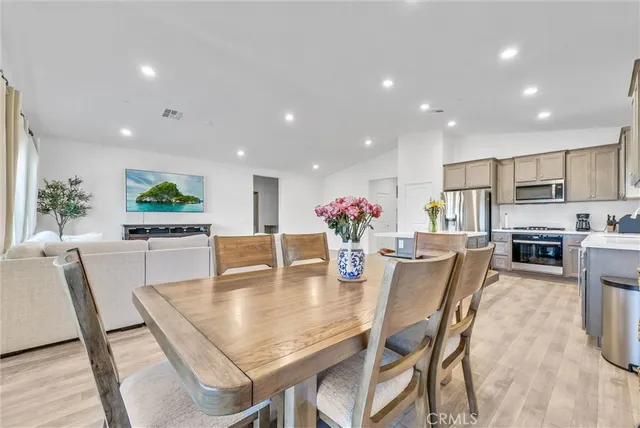 a dining room with furniture a potted plant and kitchen view