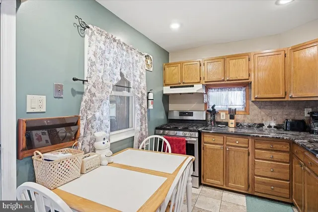 a kitchen with stainless steel appliances a stove a sink dishwasher a refrigerator white cabinets and wooden floor