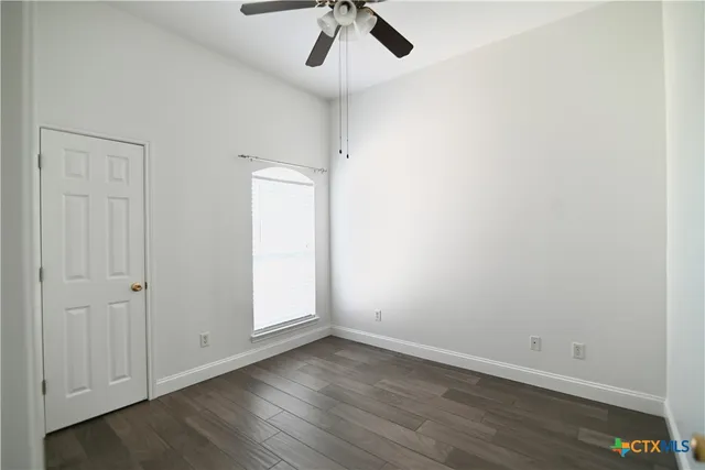 an empty room with a ceiling fan and wooden floor