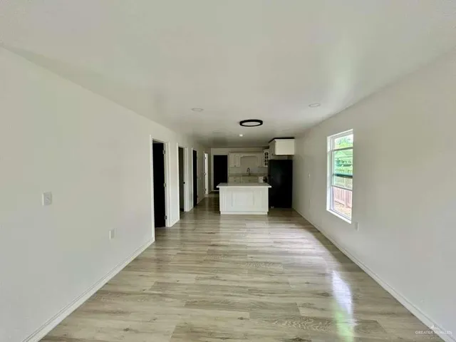 a view of a hallway with wooden floor and a window