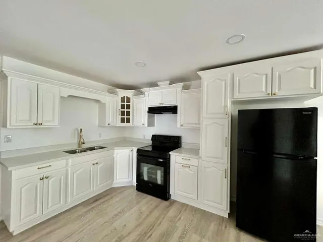 a kitchen with granite countertop a refrigerator sink and white cabinets