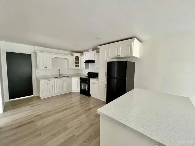 a large white kitchen with granite countertop a stove top oven a sink and dishwasher