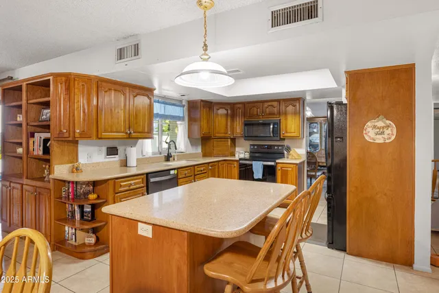 a kitchen with stainless steel appliances granite countertop a sink a stove a refrigerator with a dining table and chairs