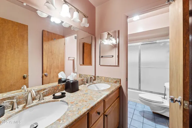 a bathroom with double vanity sinks a toilet a mirror and shower