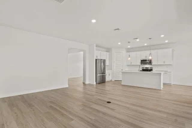 a view of kitchen with kitchen island a sink wooden floor and a refrigerator