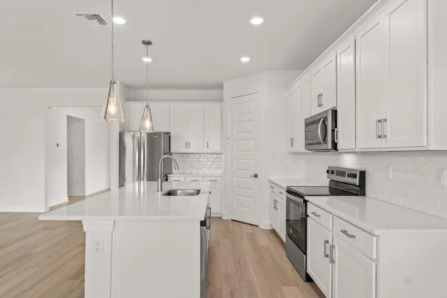 a kitchen with white cabinets and stainless steel appliances