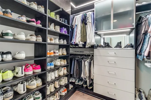 a view of walk in closet with clothes and shoes