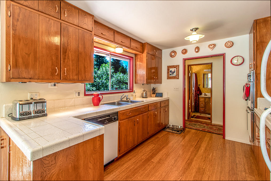 24732 Fern Valley Road Idyllwild, CA 92549 - Photo 23 of 67 a kitchen that has a lot of cabinets a sink and wooden floor