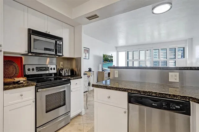 a kitchen with stainless steel appliances granite countertop a stove a sink and a microwave