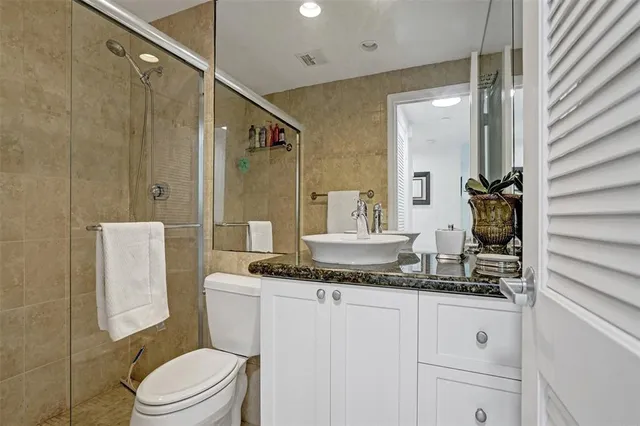 a bathroom with a granite countertop sink a mirror and a toilet
