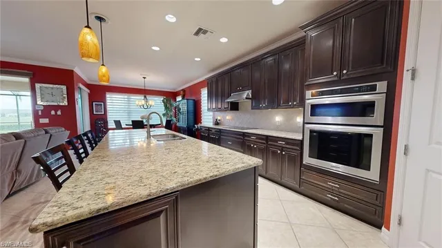 a kitchen with stainless steel appliances granite countertop a sink a stove and a wooden floors