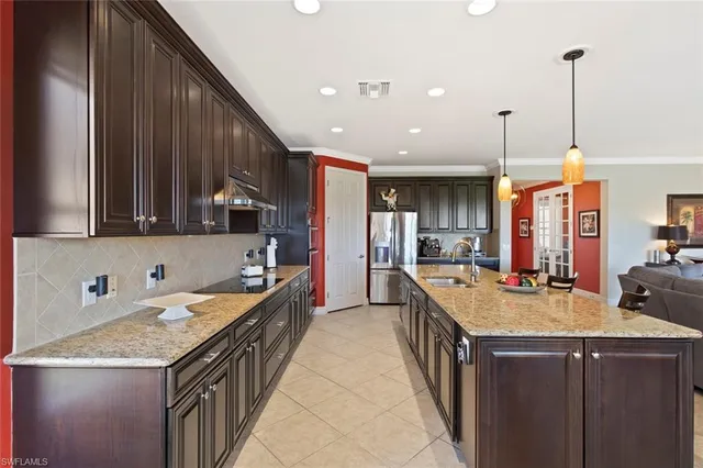 a view of a kitchen with kitchen island a large counter top stainless steel appliances and a chandelier