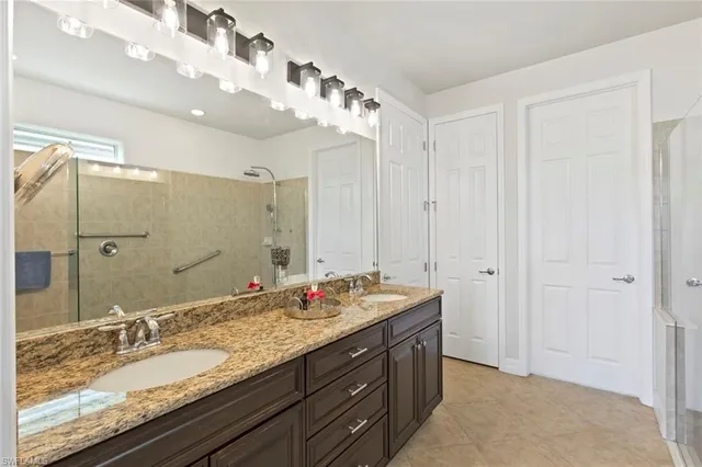 a spacious bathroom with a granite countertop sink a mirror a bathtub and shower