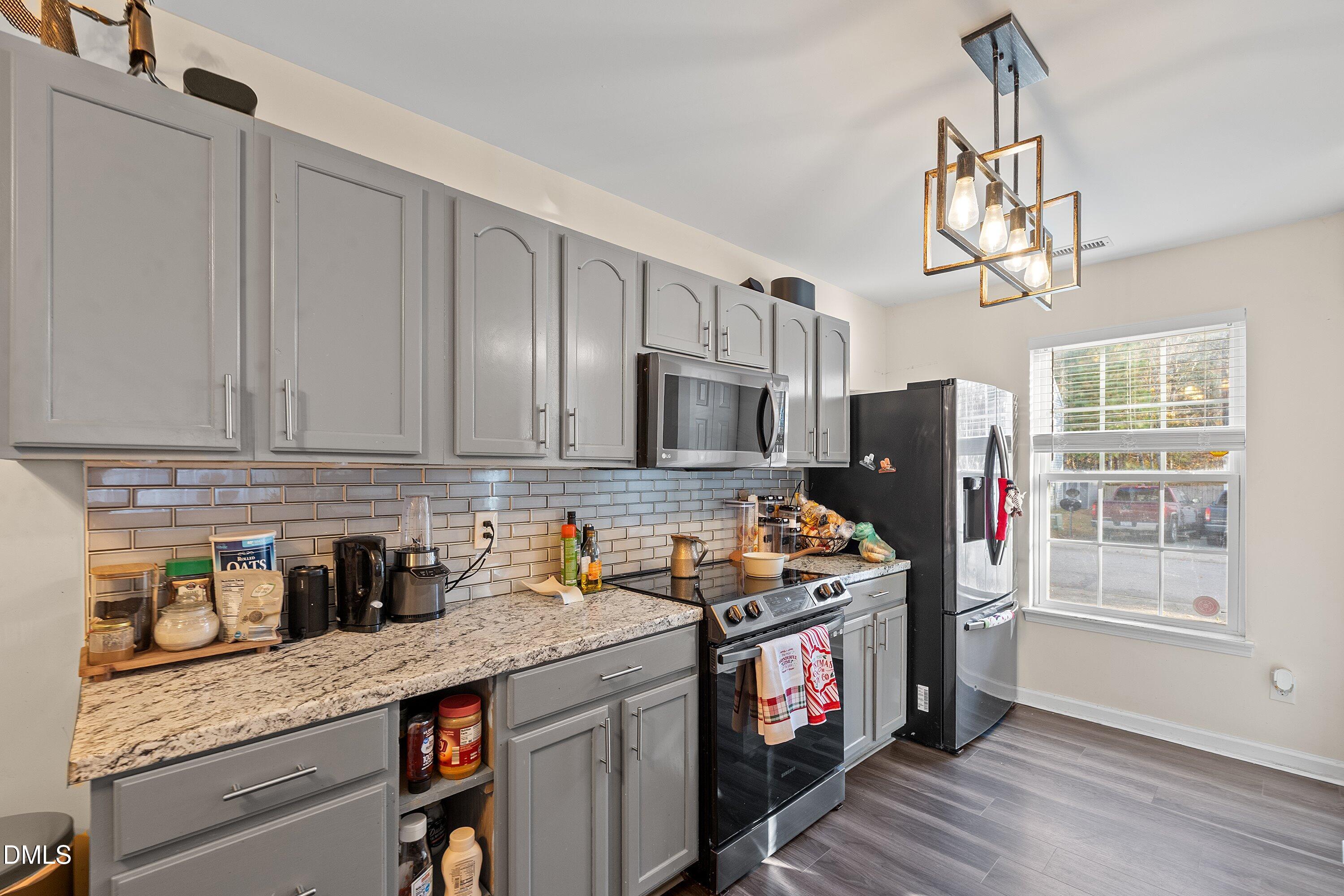 2027 Buffalo Way Durham, NC 27704 - Photo 11 of 30 a kitchen with stainless steel appliances granite countertop a stove a sink dishwasher and a refrigerator with wooden floor