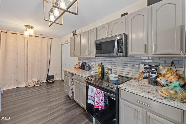 a kitchen with stainless steel appliances granite countertop a stove a sink dishwasher and microwave with wooden floor