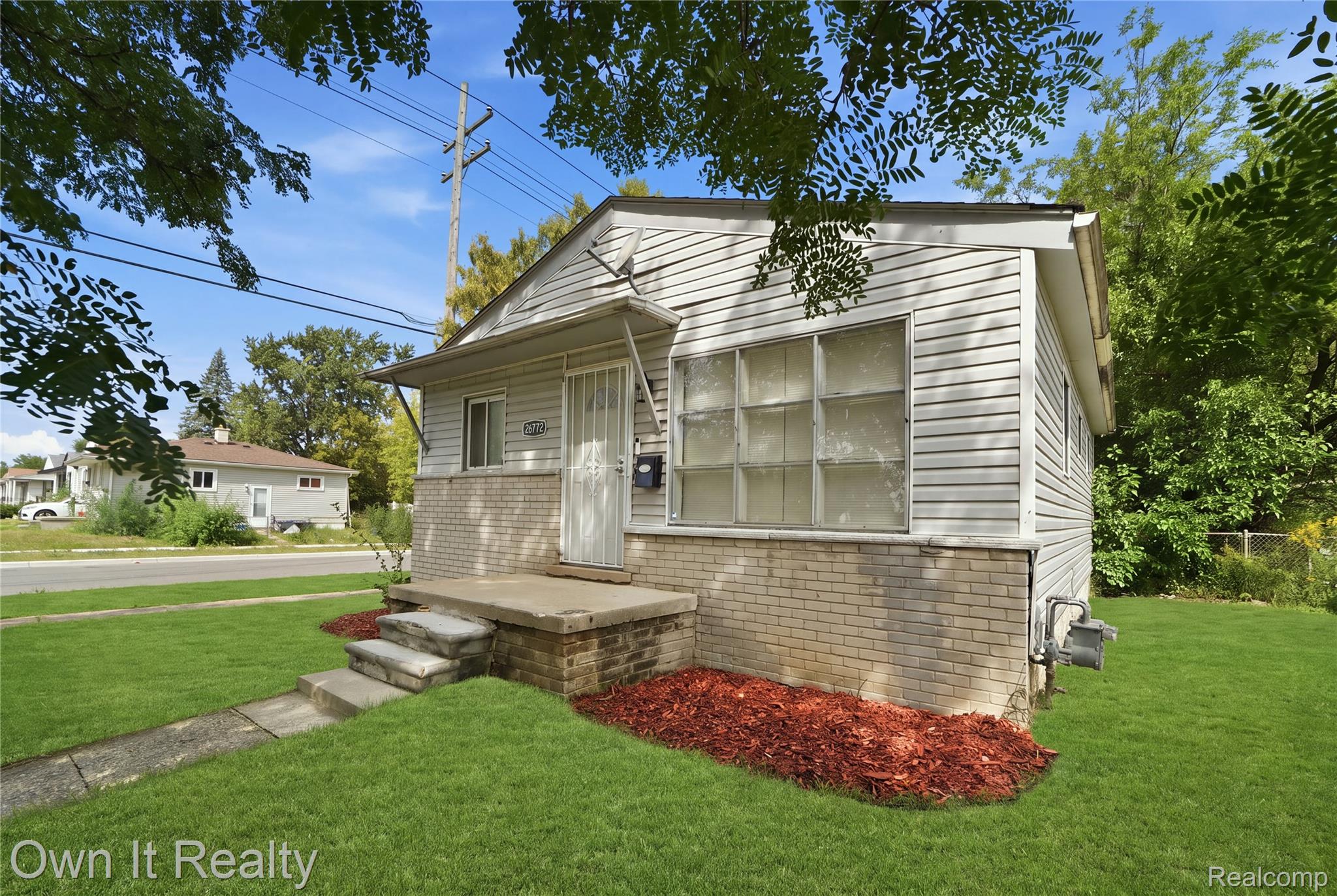 26772 Colgate Street Inkster, MI 48141 - Photo 3 of 25 White siding exterior with a brick foundation, a front entry with a security screen door, and a manicured lawn