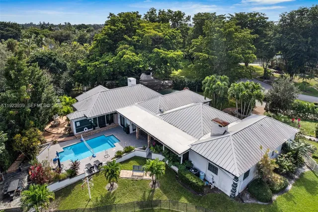 an aerial view of a house with swimming pool and outdoor seating