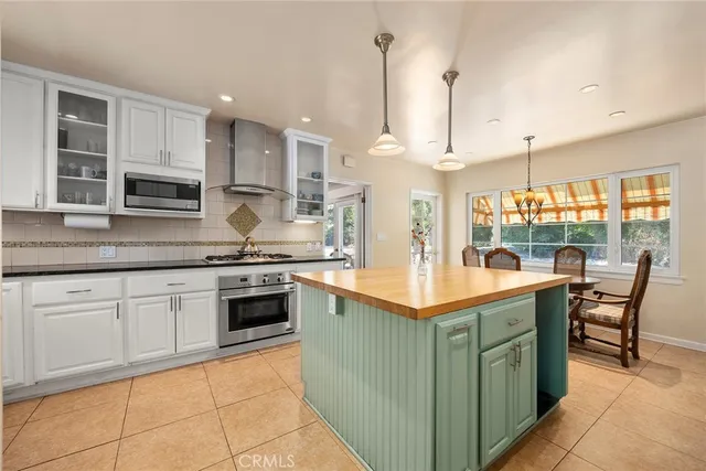 a kitchen with stainless steel appliances granite countertop a stove top oven a sink dishwasher a dining table and chairs with wooden floor