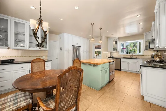 a kitchen with stainless steel appliances kitchen island granite countertop a sink a stove a dining table and chairs