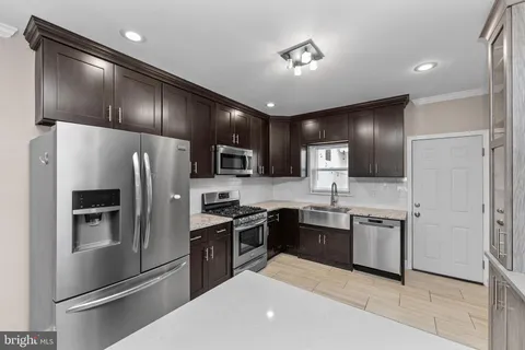 a kitchen with stainless steel appliances granite countertop a refrigerator a sink dishwasher a stove and white cabinets with wooden floor