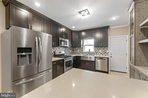 a kitchen with granite countertop stainless steel appliances cabinets a sink and a refrigerator
