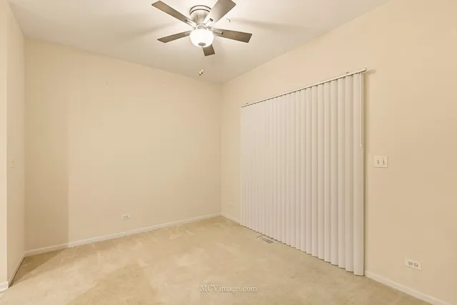 an empty room with a chandelier fan and windows