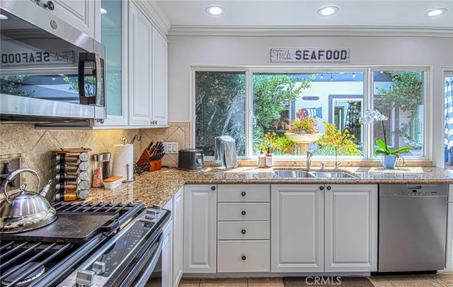 a kitchen with granite countertop a stove a sink and a wooden cabinets