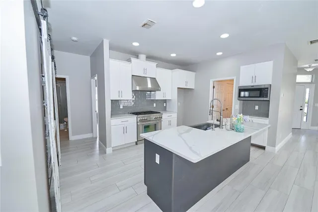 a kitchen with stainless steel appliances a white refrigerator a stove a sink and a refrigerator