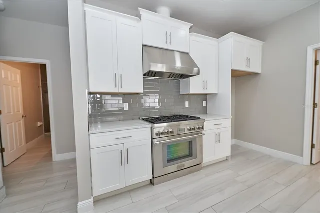 a large kitchen with cabinets wooden floor and stainless steel appliances